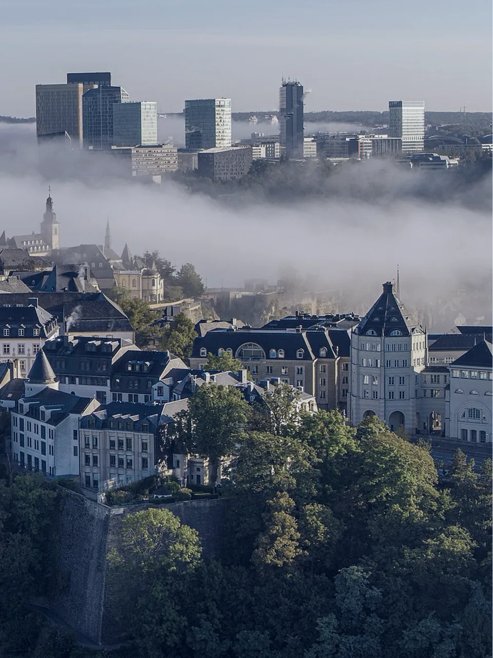 Vue de Luxembourg-Ville au petit matin : le quartier financier du Kirchberg émerge d’une nappe de brouillard au-dessus de la vieille ville et de ses fortifications.